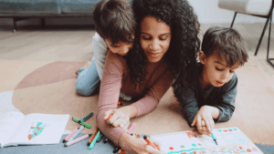 Mother sitting with two children calmly coloring together in a cozy home setting, showing connection and co-regulation.