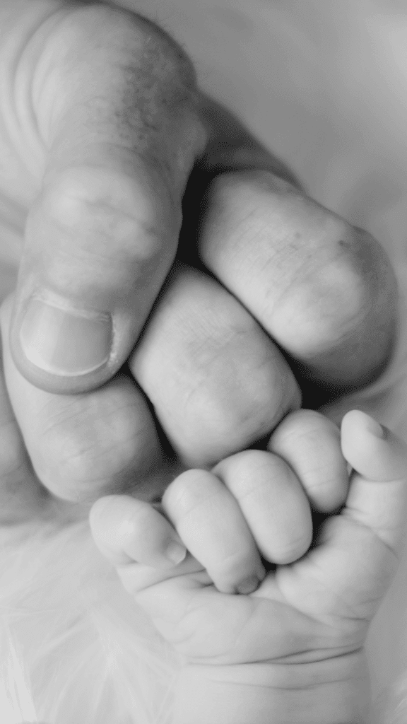 Parent holding baby’s hand symbolizing trust, safety, and emotional connection
